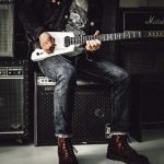 man sitting on guitar amplifier playing electric guitar
