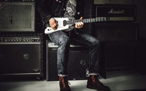 man sitting on guitar amplifier playing electric guitar