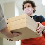 man wearing a face mask delivering pizza