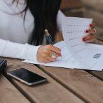 crop woman taking notes in calendar