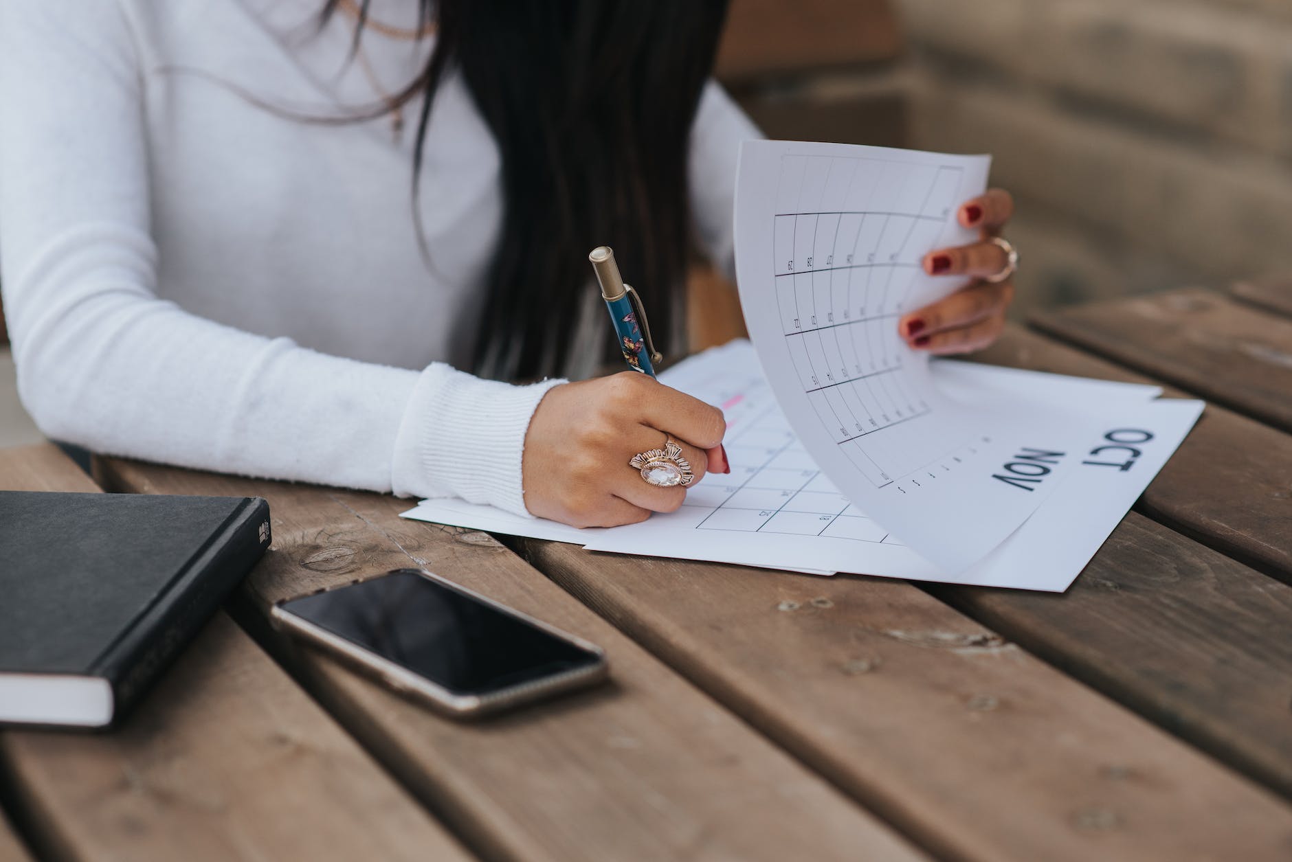 crop woman taking notes in calendar