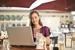 woman wearing purple shirt holding smartphone white sitting on chair