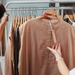 crop asian shoppers interacting while choosing clothes in shop